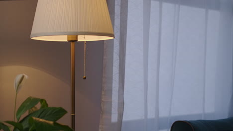 woman-is-walking-in-living-room-and-turning-off-floor-lamp-in-apartment-at-evening-time-details-shot-interior-of-modern-cozy-flat